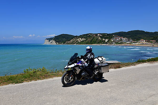 Eine Frau fährt am Meer in Griechenland Motorrad