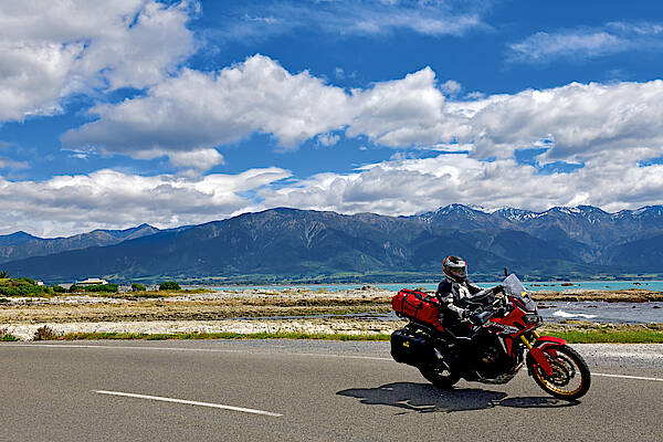 Ein Motorrad fährt am Meer in Neuseeland entlang